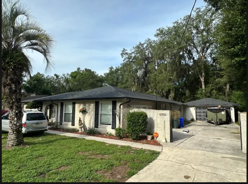 Hip roof with dark asphalt shingles on single-family home with carport